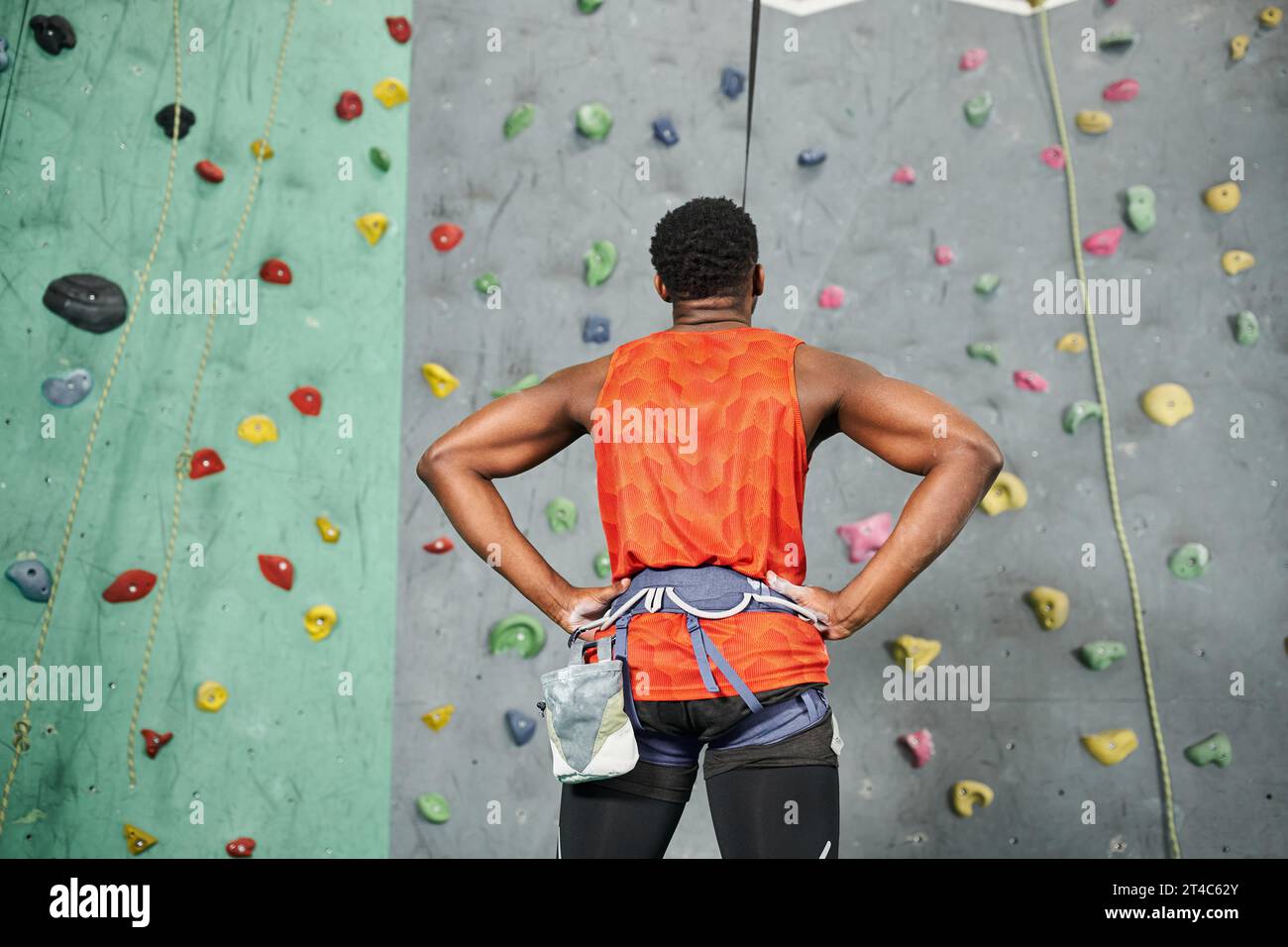 back view of sporty african american man ready to climb up bouldering