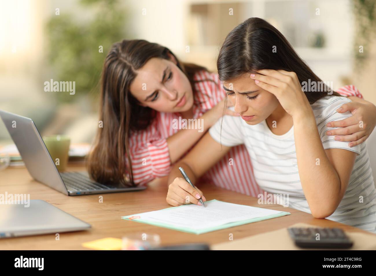 Worker comforting a sad colleague signing contract tele working at home Stock Photo