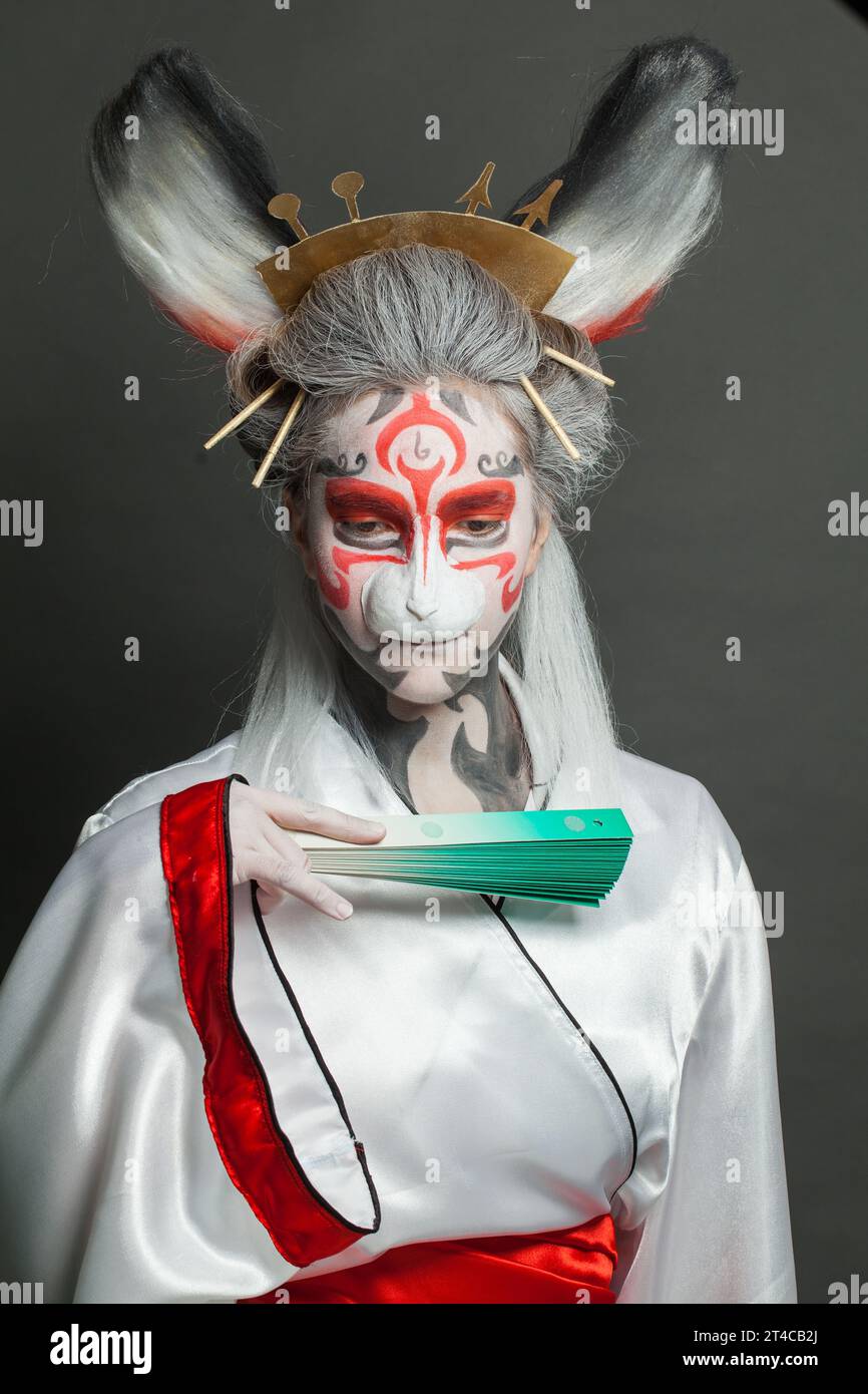 Actress woman with animal makeup, mask and stage asian costume posing on black background. Halloween, carnival, performance and theater concept Stock Photo