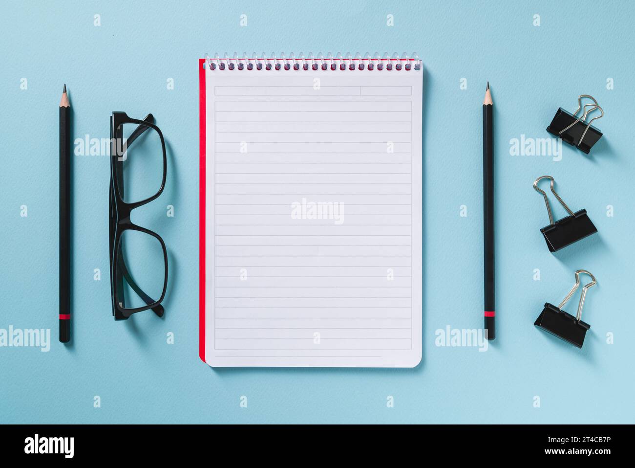 Top view of empty notebook, glasses and pen on blue office desk Stock Photo