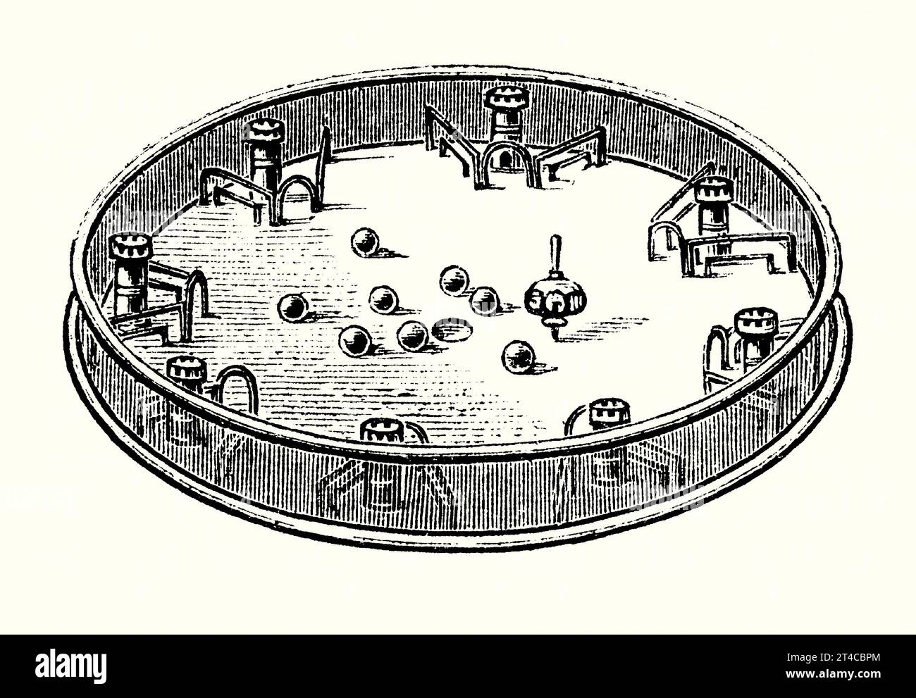 An old engraving of the game of Cannonade or Castle bagatelle. It is from Victorian book of the 1890s on sports, games and pastimes. It comprising a circular wooden board, about 40cms in diameter, with a metal mesh outer ‘fence’. Around the board were eight castles or ‘stations’ (often made of turned ivory) within wire frames. The board also housed a spinning top or ‘teetotem’ and eight clay or ivory balls. Each player in turn would vigorously spin the top, which would then hit and scatter the balls. The aim was to get as many balls as possible housed in their opponents’ perimeter castles. Stock Photo