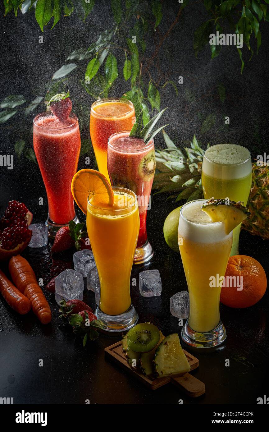 A picture of several cups of various natural juices on a black background, pineapple, carrot, orange and apple juice Stock Photo