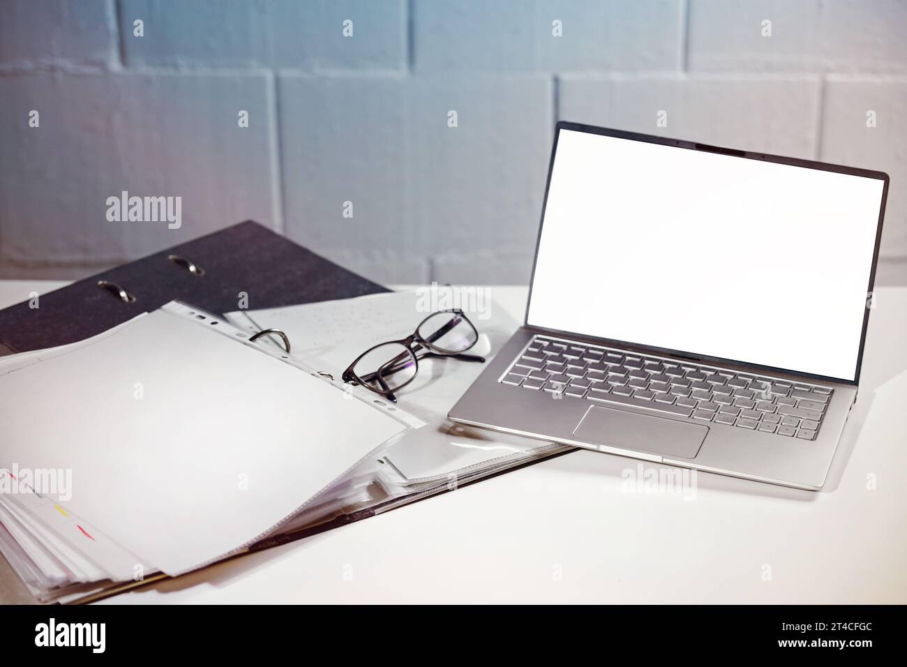 Laptop with white monitor mock up, glasses and a ring binder on an office desk, concept for accounting, finance and business, copy space, selected foc Stock Photo