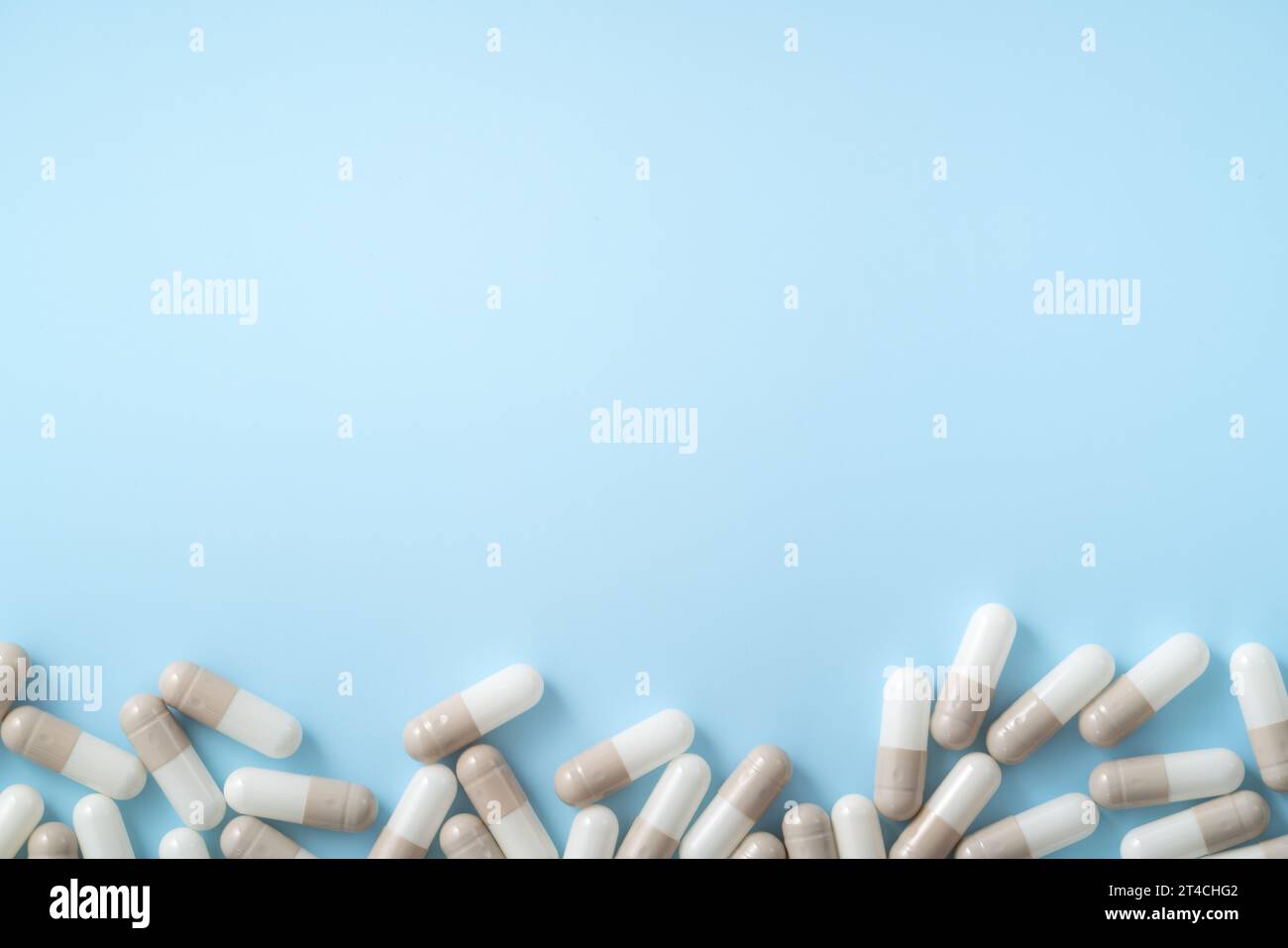 Taking medicine design concept, top view of capsule pills spilled over blue table background. Stock Photo