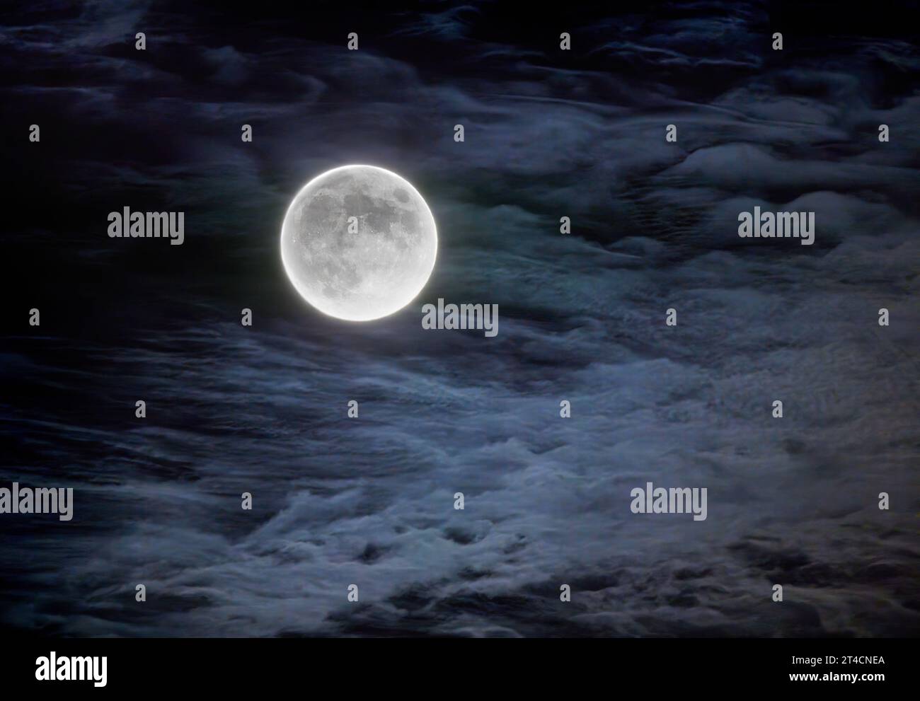 Hunter's full moon in October glowing among the clouds in the night sky over Canada Stock Photo