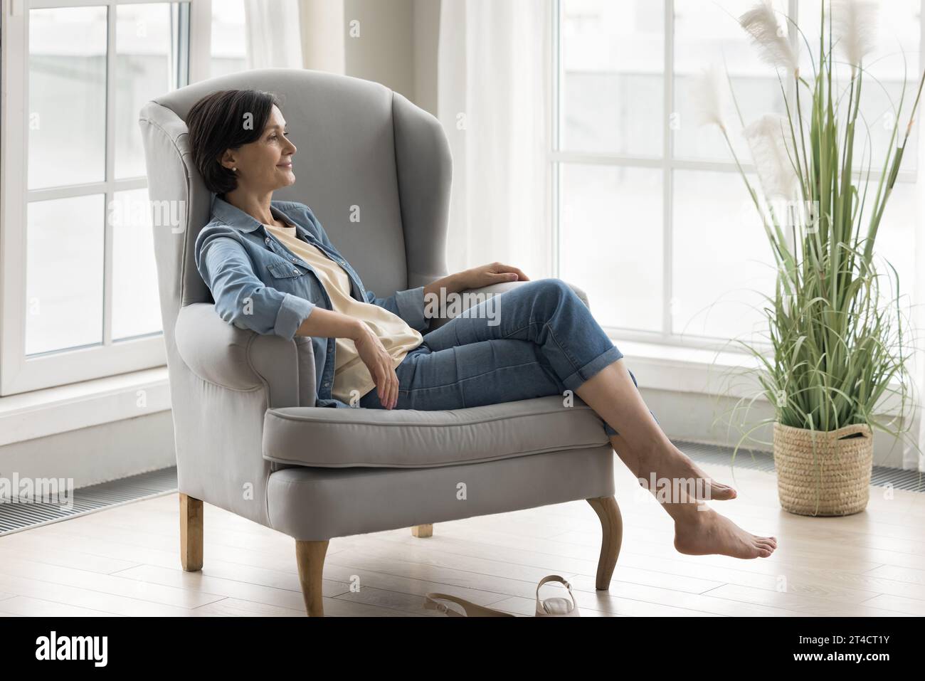 Dreamy older woman relaxing at home sitting on comfy armchair Stock ...