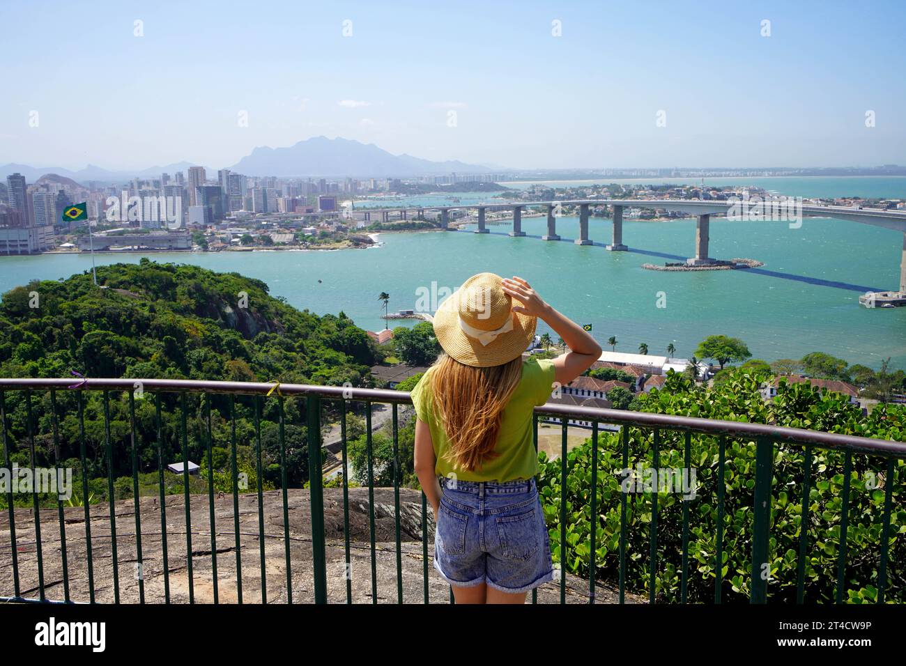 Holidays in Brazil. Back view of young traveler woman enjoying Vitoria cityscape with Terceira Ponte bridge, Vitoria, Espirito Santo, Brazil. Stock Photo