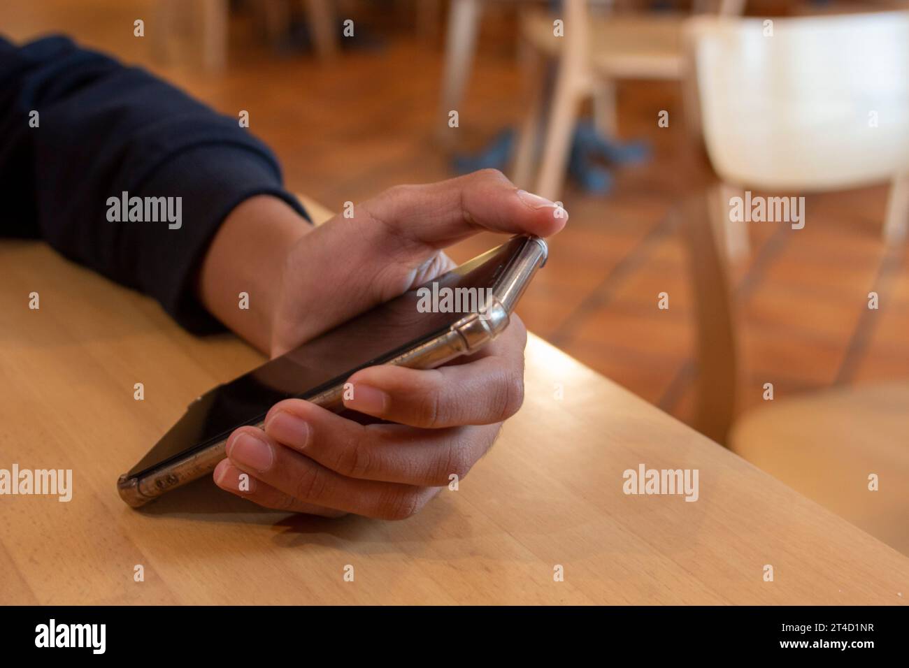 African American woman's hand holding a mobile phone on a bar table ...