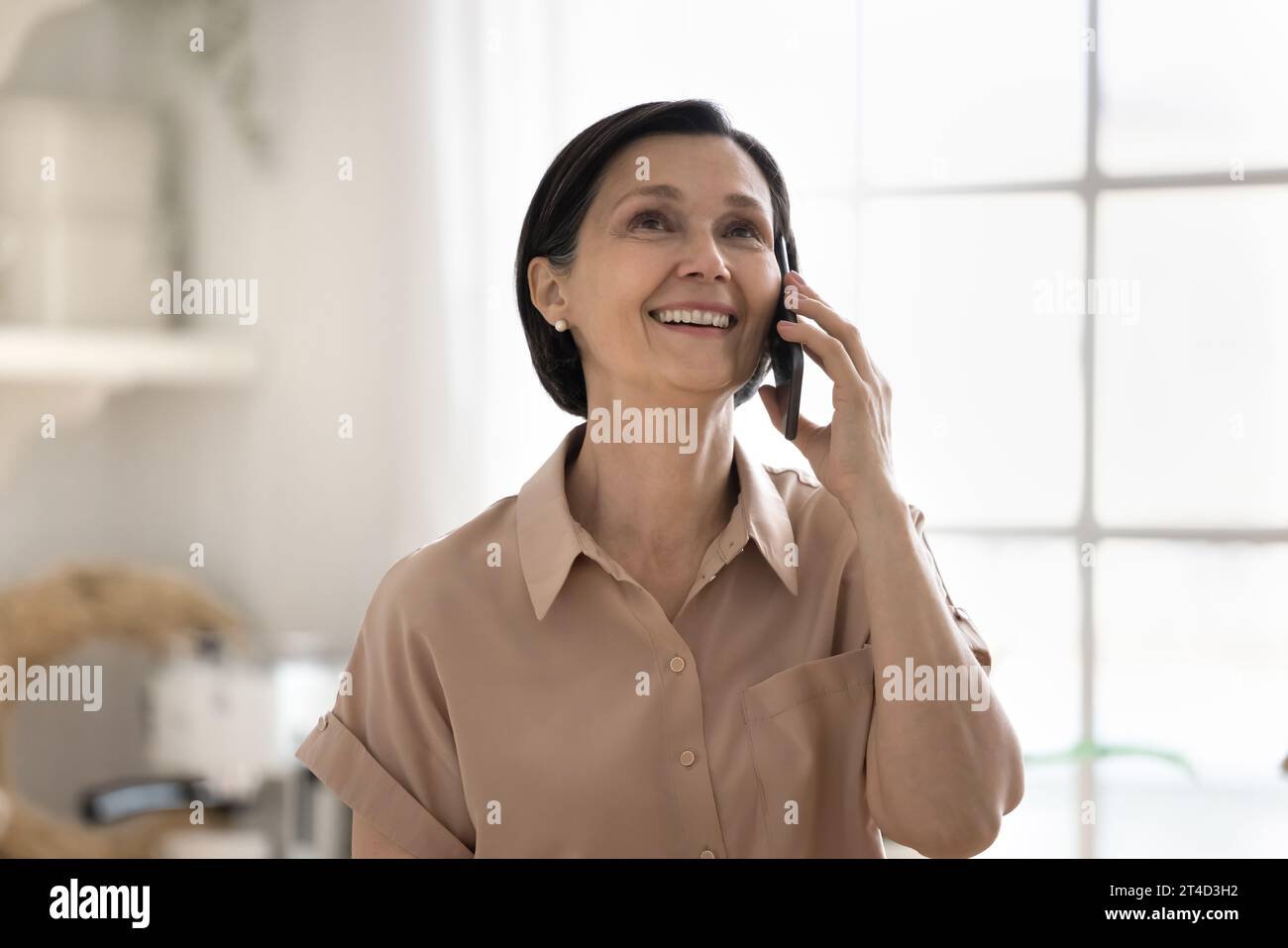 Happy attractive aged woman enjoy conversation on cellphone Stock Photo