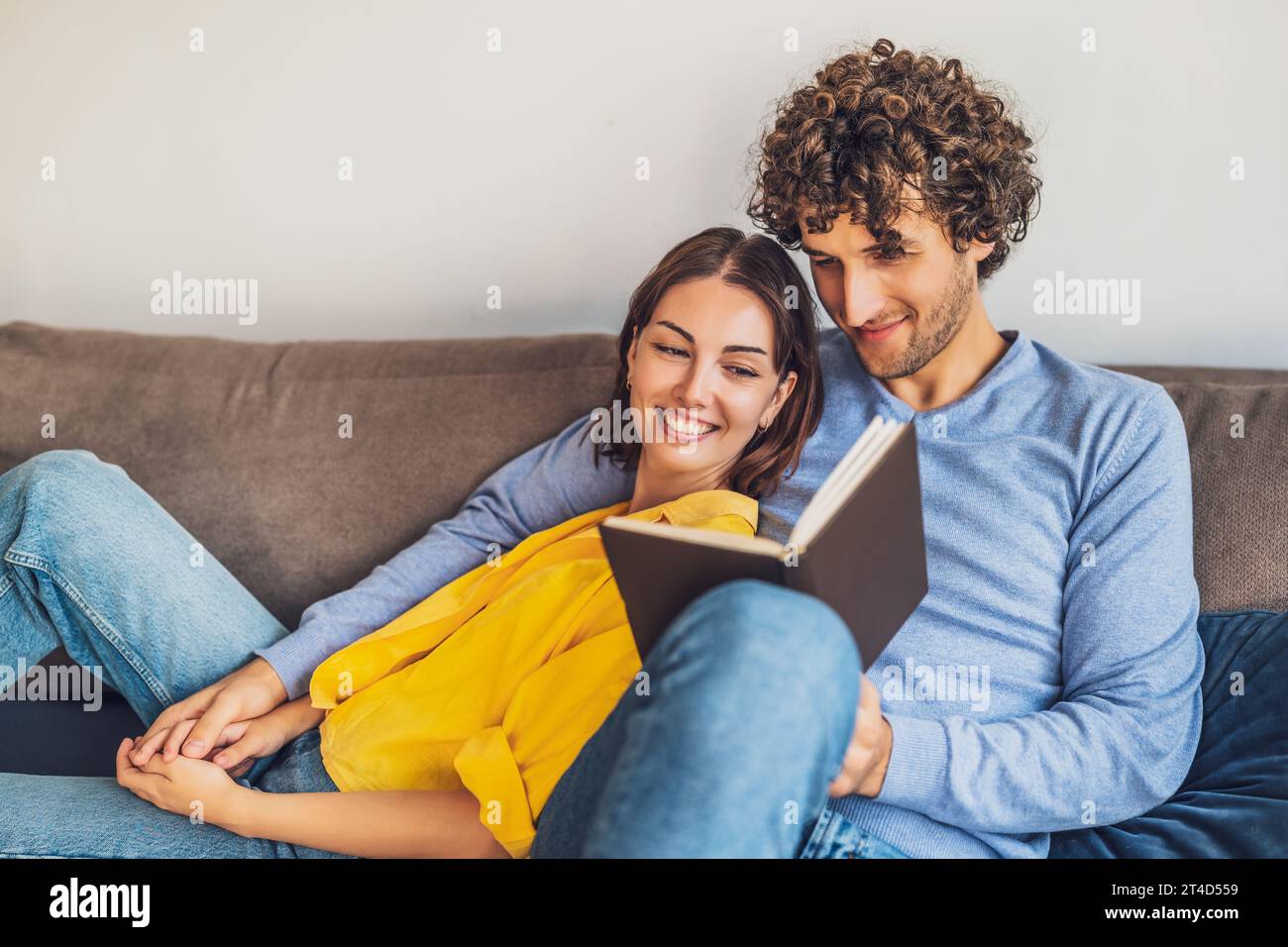 Portrait of young happy couple at home. They are relaxing at sofa. Stock Photo