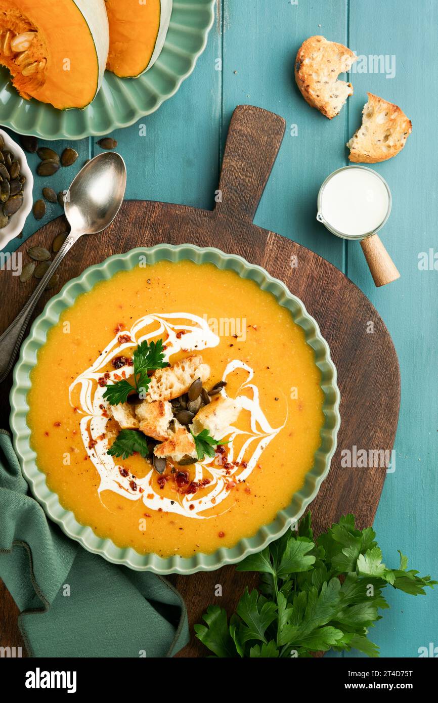 Pumpkin and carrot cream soup with herbs, seasonings and seeds in bowl on dark wooden background in rustic style. Thanksgiving traditional autumn pump Stock Photo