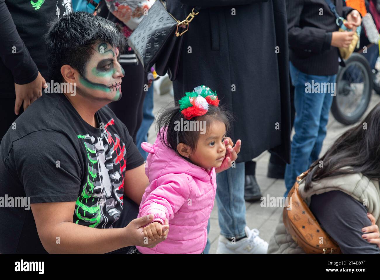 Detroit, Michigan - A man and a child watch dancers at the Day of the Dead celebration at Valade Park on the Detroit Riverfront. Stock Photo