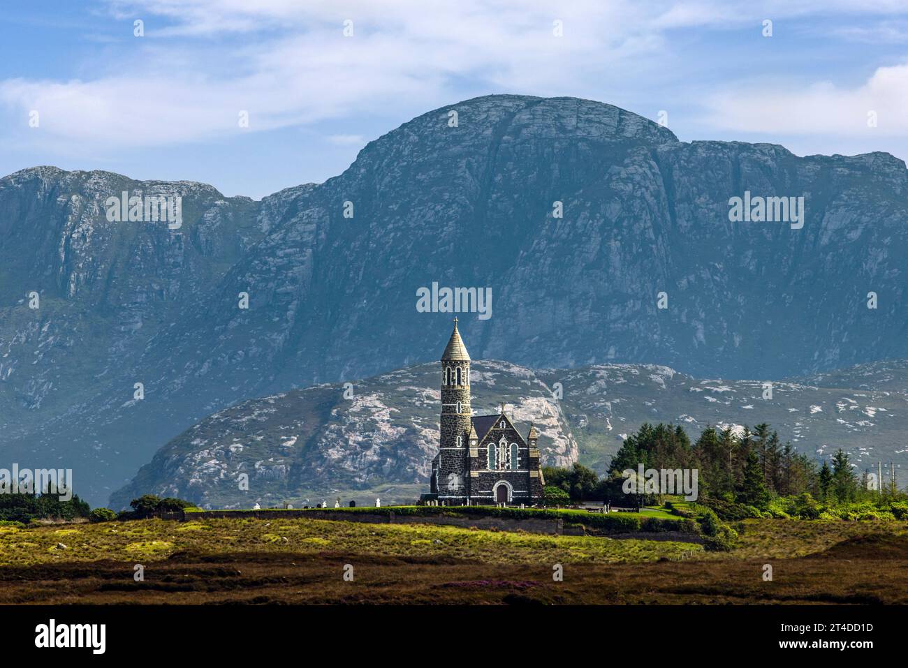 The Sacred Heart Catholic Church in Dunlewey, Ireland, is a landmark with its Hiberno-Romanesque style and round tower, nestled between Mount Errigal Stock Photo