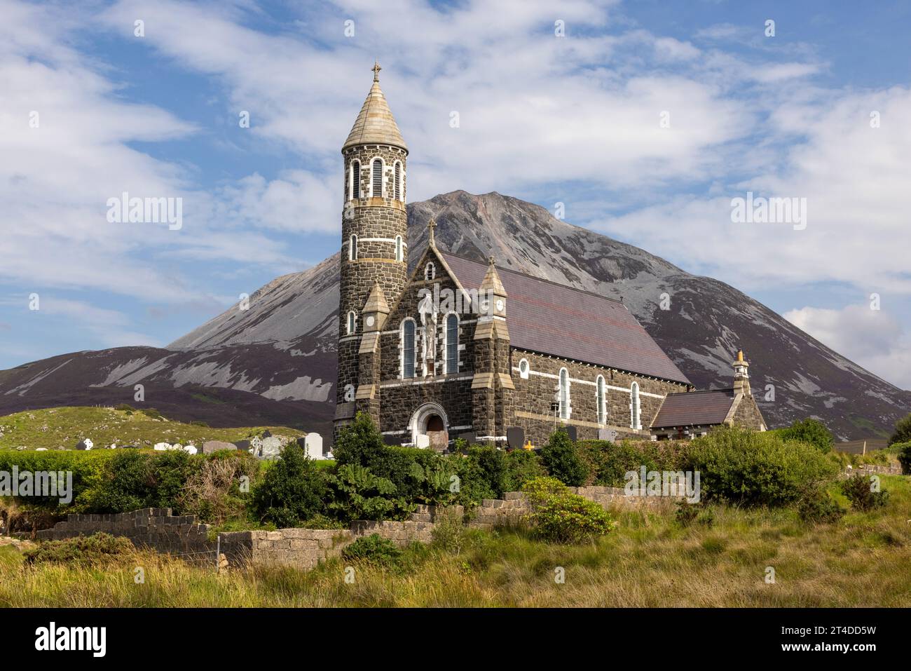 The Sacred Heart Catholic Church in Dunlewey, Ireland, is a landmark with its Hiberno-Romanesque style and round tower, nestled between Mount Errigal Stock Photo