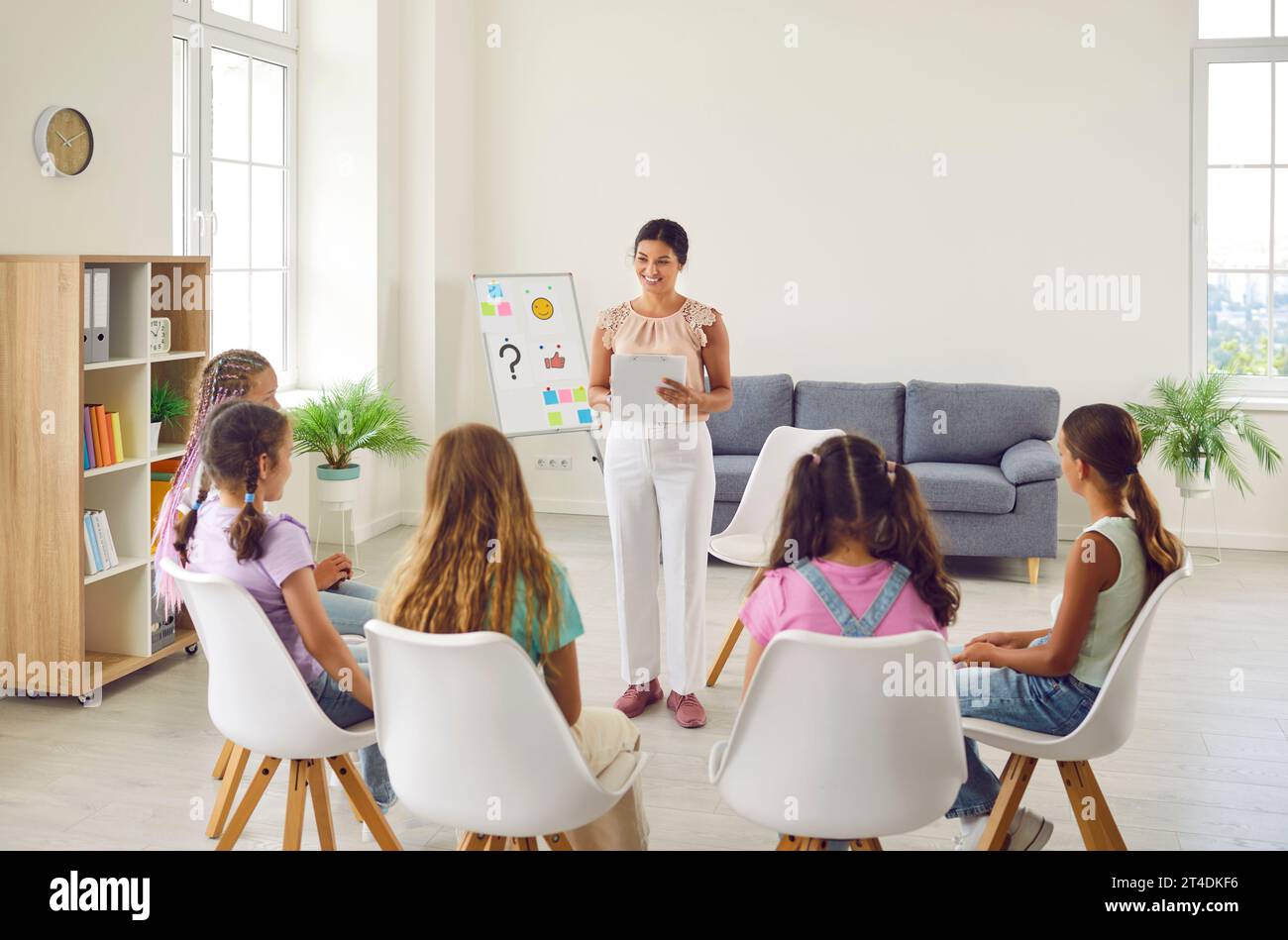 Friendly woman conducting psychological training for a group of school children girls. Stock Photo