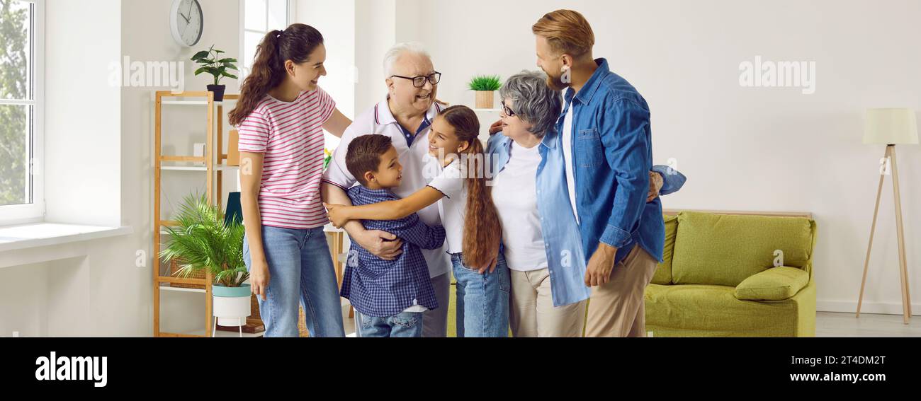 Happy multi-generational family who are happy to see each other hugging while meeting at home. Stock Photo