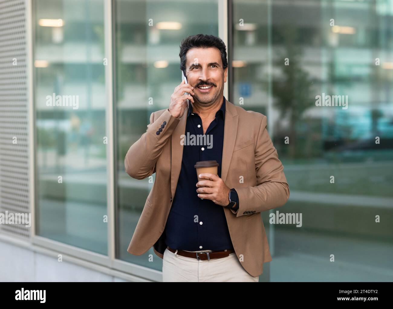 Middle eastern businessman talking on phone while walking by street Stock Photo