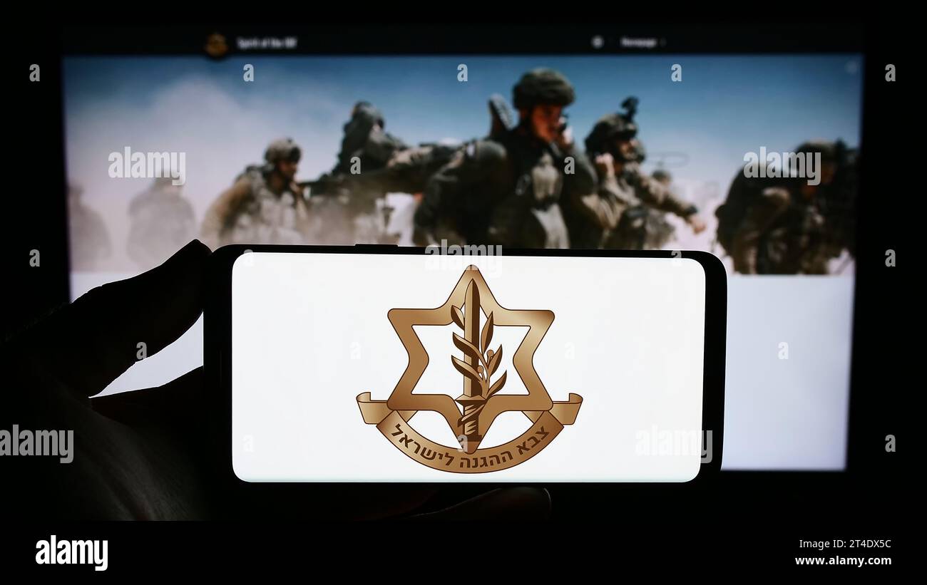 Person holding smartphone with logo of national military Israel Defense Forces (IDF) in front of website. Focus on phone display. Stock Photo