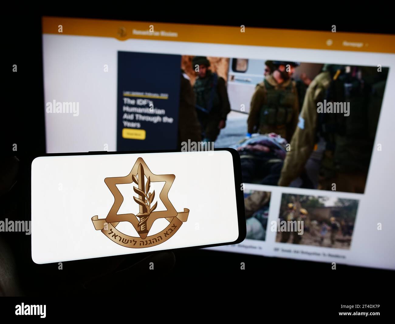 Person holding cellphone with logo of national military Israel Defense Forces (IDF) in front of webpage. Focus on phone display. Stock Photo