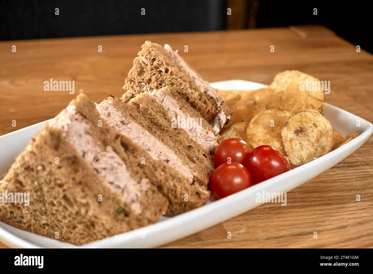 Tuna sandwich, brown bread, potato crisps, cherry tomatoes Stock Photo
