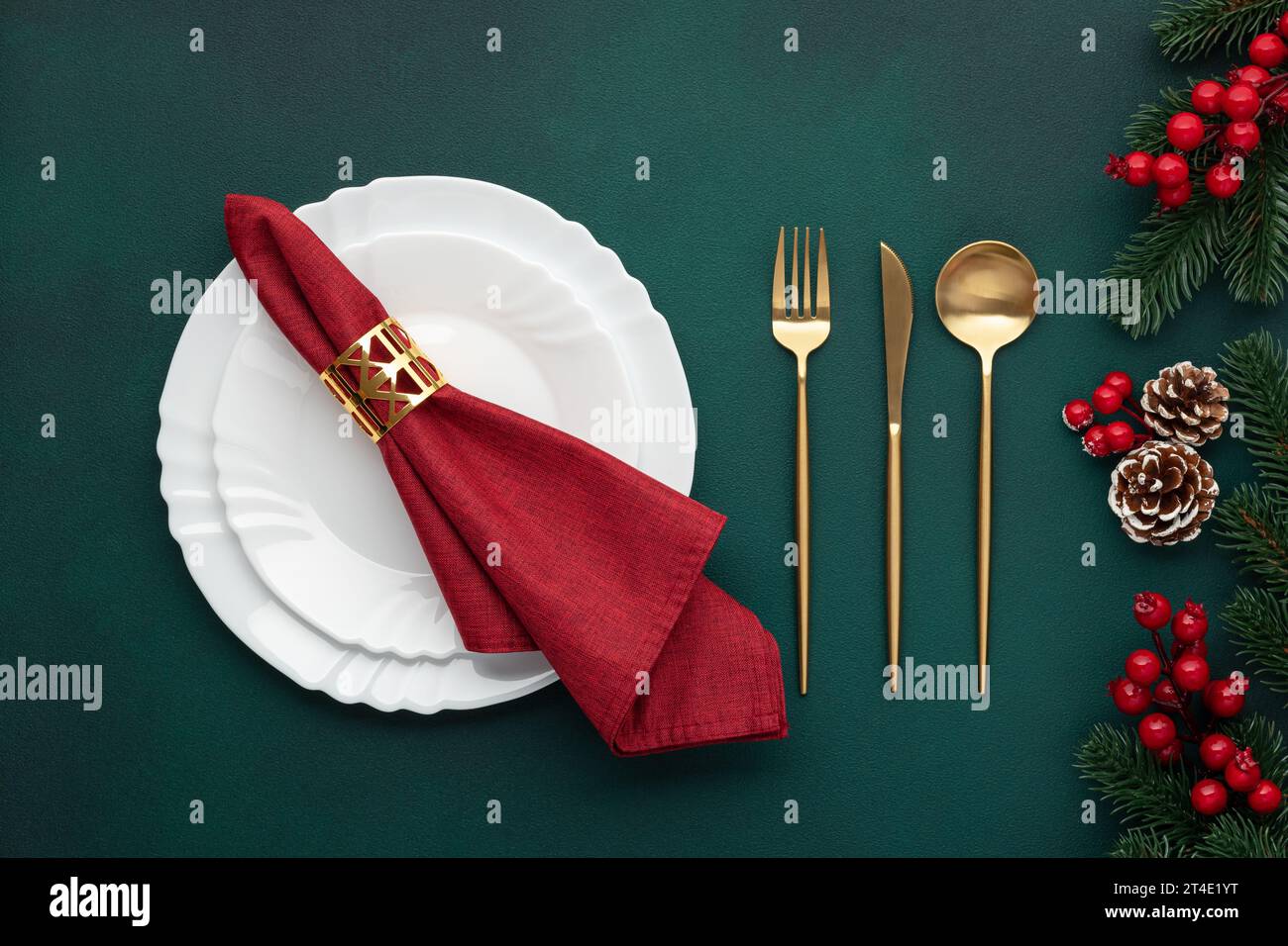 Clean plate, gold cutlery. Festive table setting with christmas decorations. Celebration xmas eve: flat arrangement. Red, golden accents. Fir cones on Stock Photo