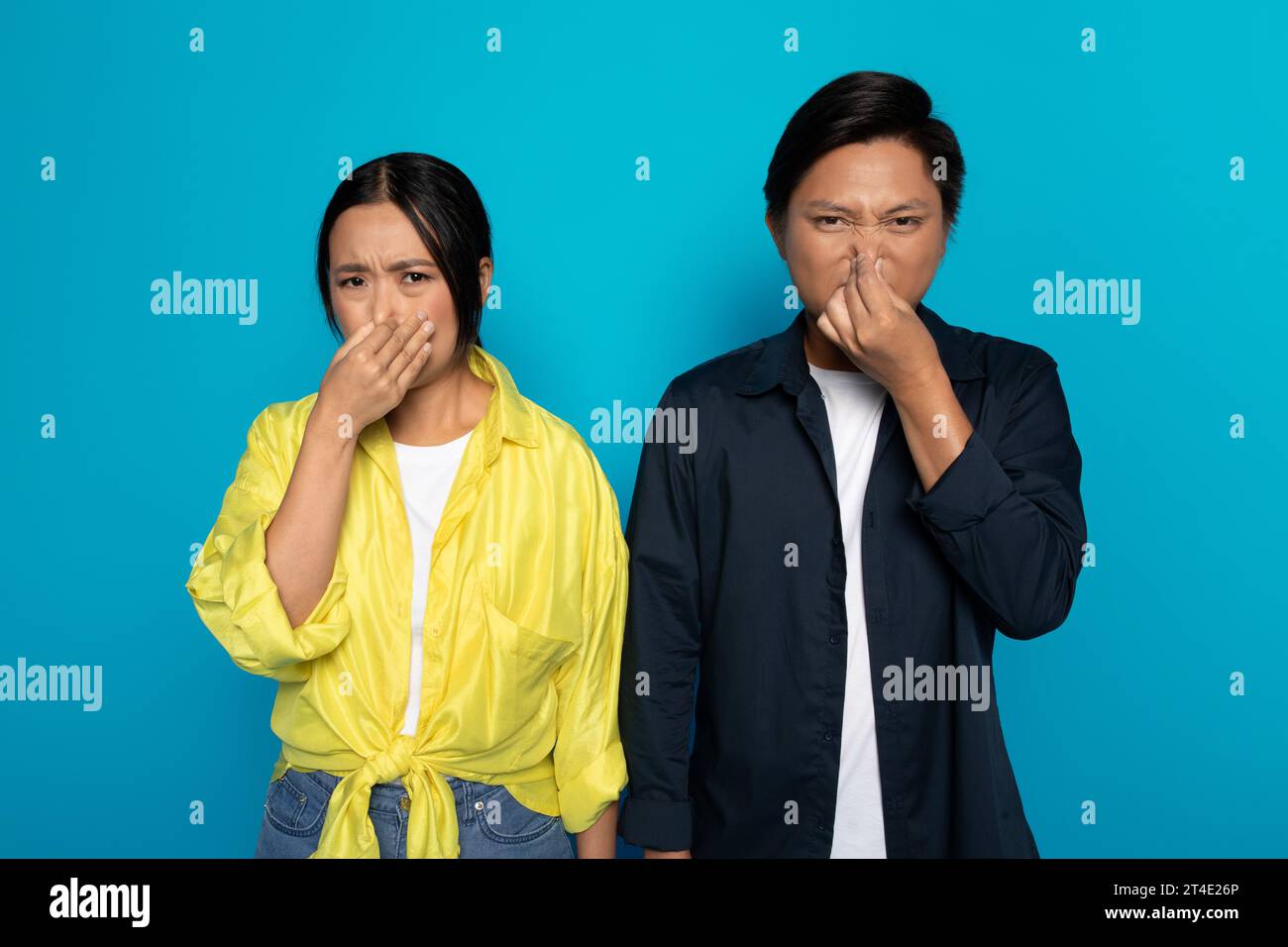 Upset sad millennial asian couple in casual covers nose with hands, suffers from stench Stock Photo