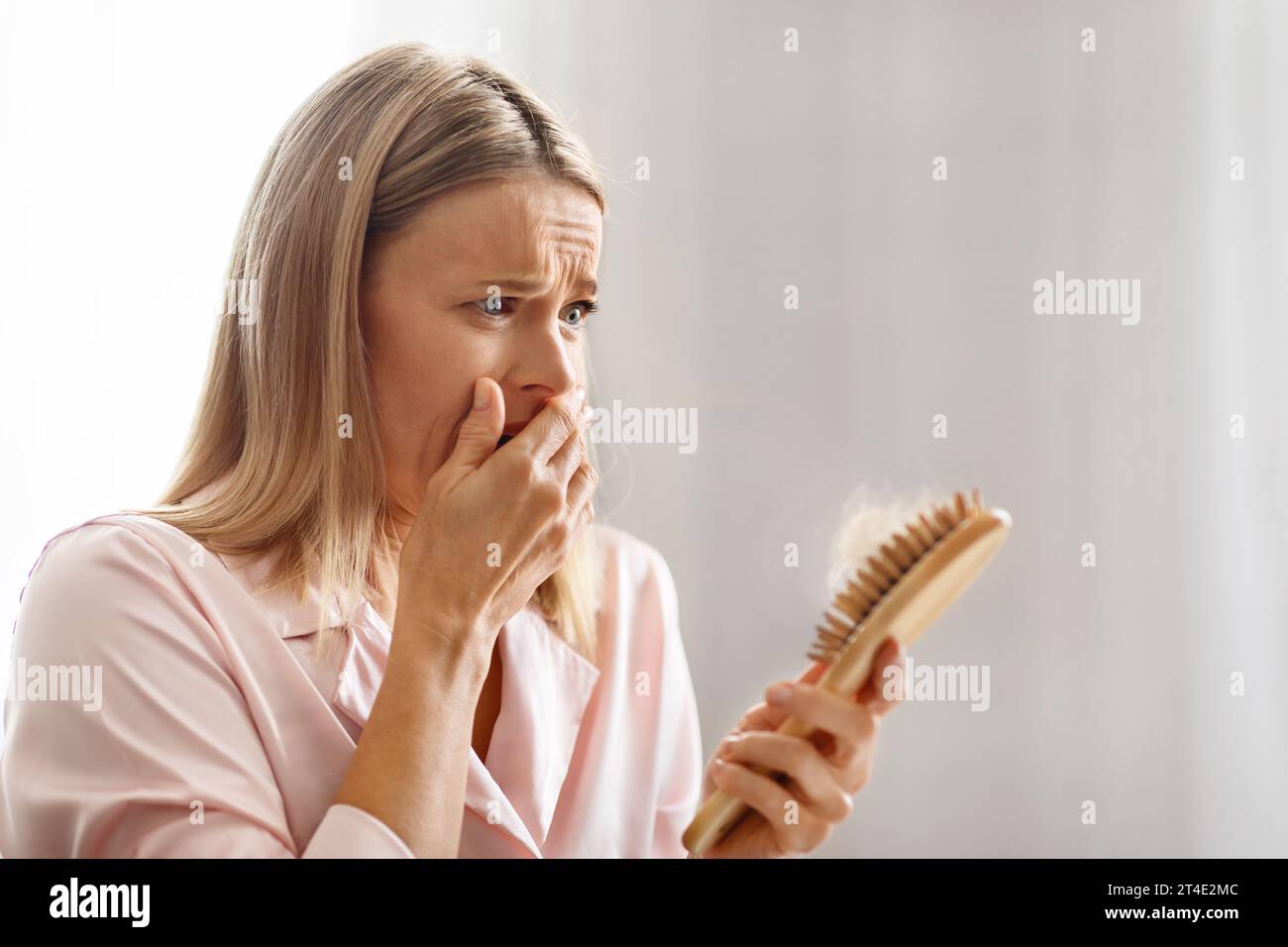Shocked Middle Aged Female Holding Brush Full Of Fallen Hair Stock Photo