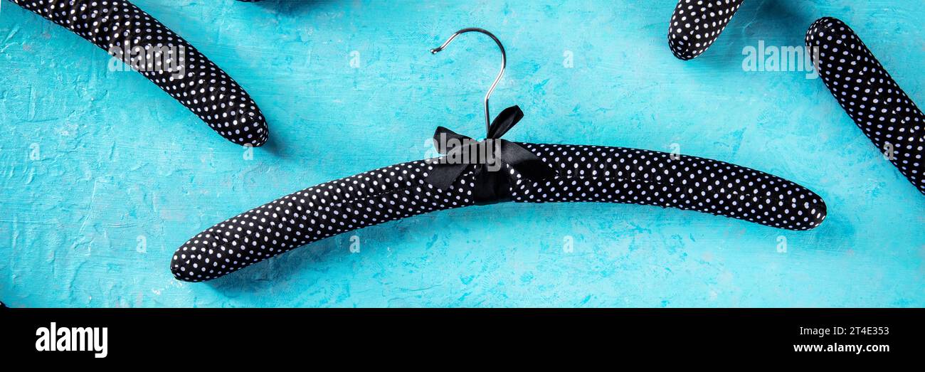 Fashion collection panorama. Black satin hangers for delicate clothes, a flat lay layout on blue