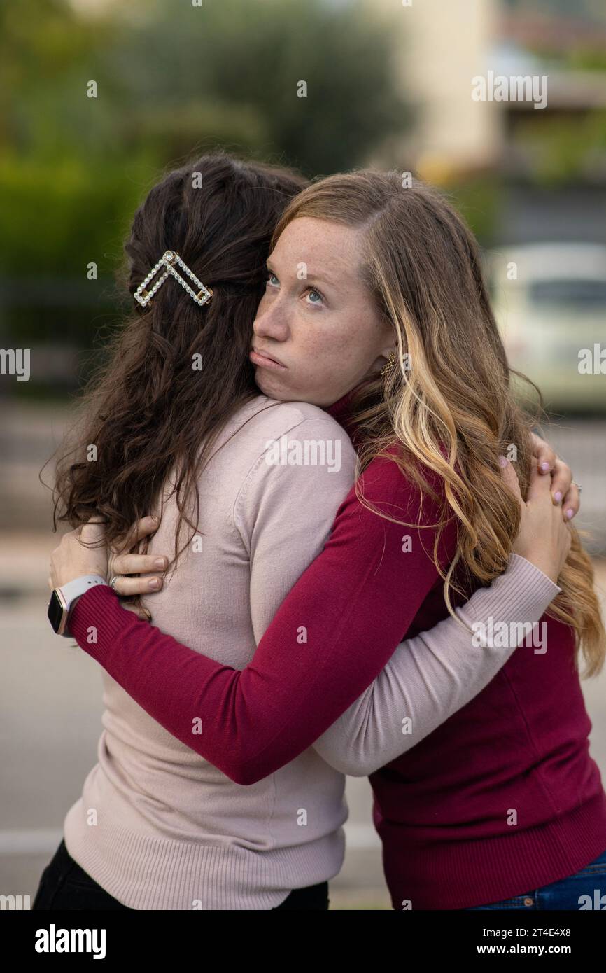 Hypocritical girl hugs a friend but gets bored of being close to her. Fake Friendship concept. Stock Photo