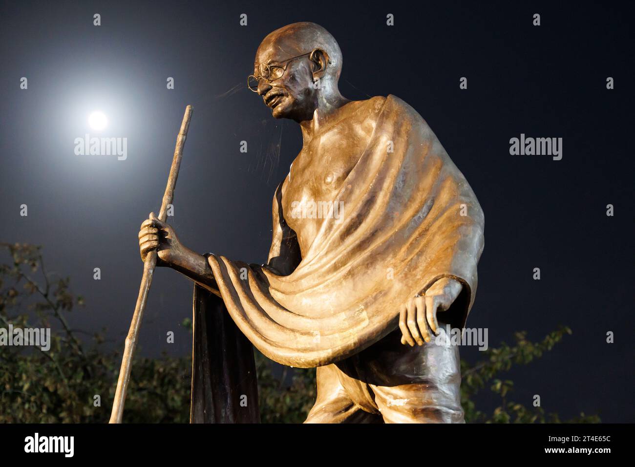 The statue of Mahatma Gandhi situated on the Belgrave Road, Leicester. The picture was taken at night with the light of the moon shining on the statue. The statue has been the scene of protests to remove the statue. The statue sits alongside the Golden Mile, the area where the main Diwali celebrations are held every year. Stock Photo