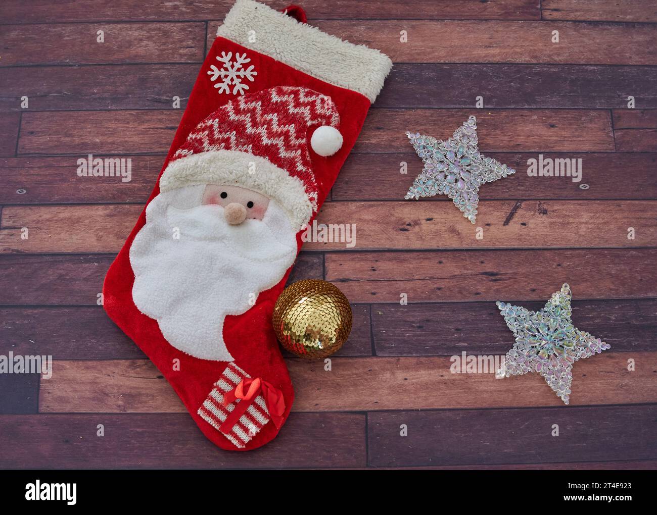 Christmas decoration. Santa red stocking with shining stars and a golden ball. Wooden background. horizontal Stock Photo