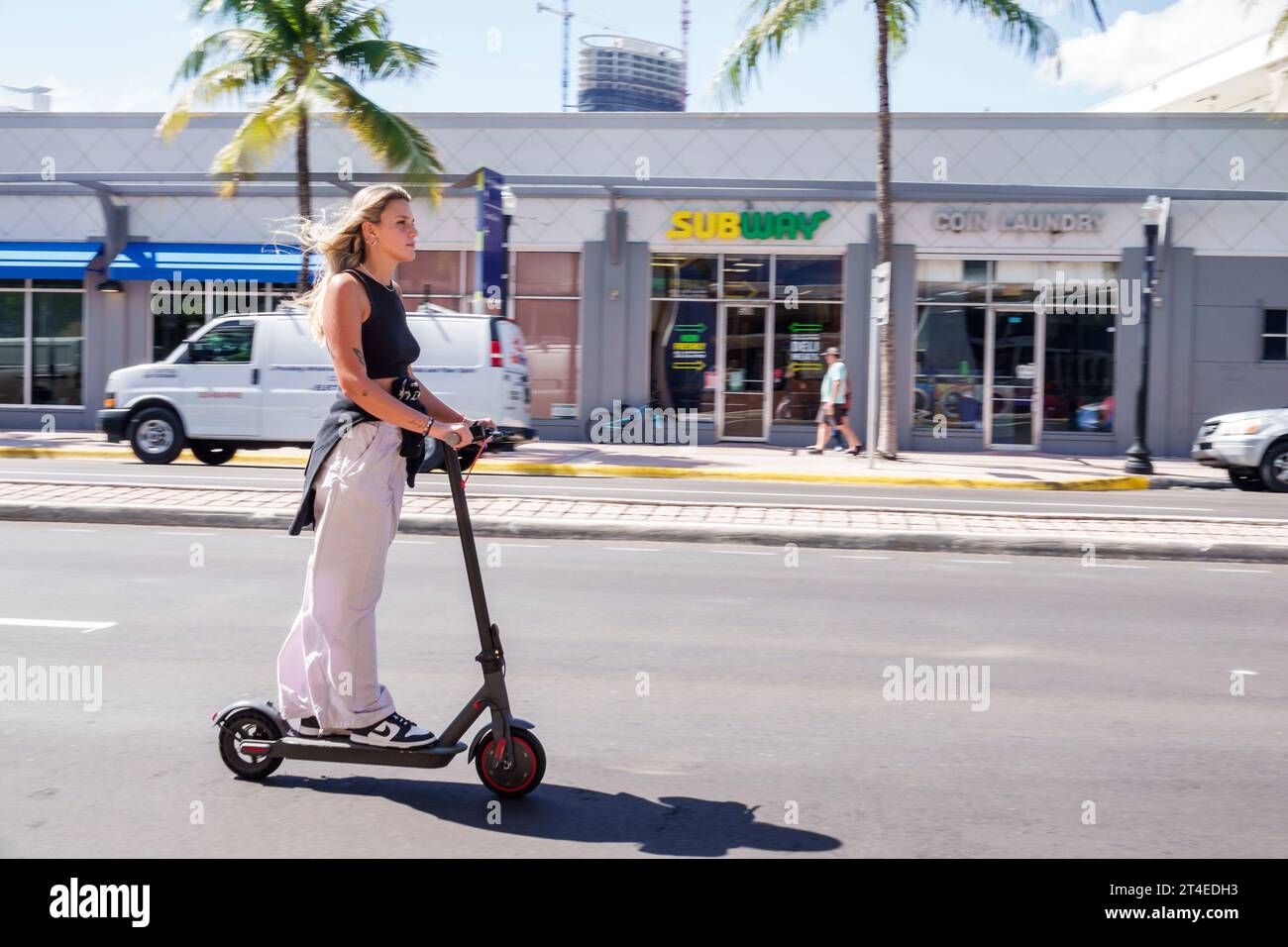 Miami Beach Florida,riding driving electric scooter street,woman women lady female,adult,resident Stock Photo