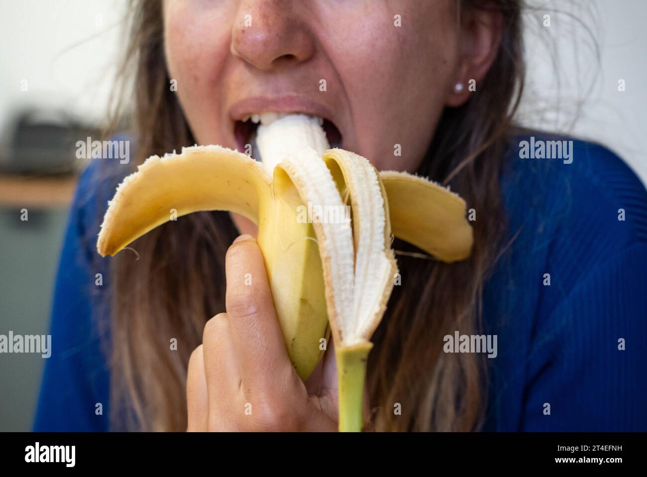 Woman eats food. Woman eats  banana. Close shot of girl eating  bananas. Face while eating banana Stock Photo