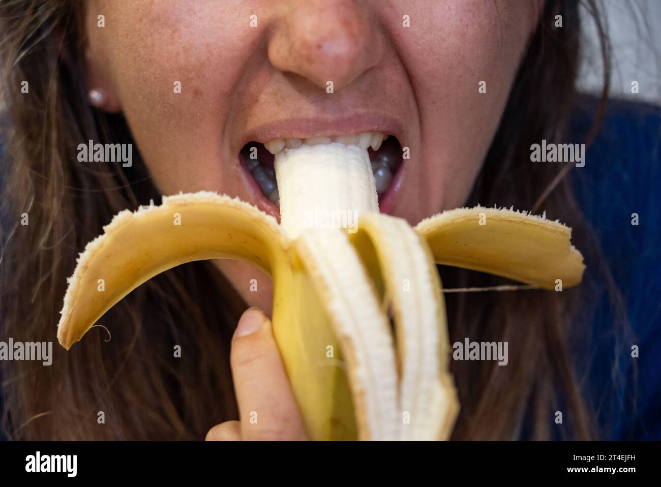 Woman eats food. Woman eats  banana. Close shot of girl eating  bananas. Face while eating banana Stock Photo