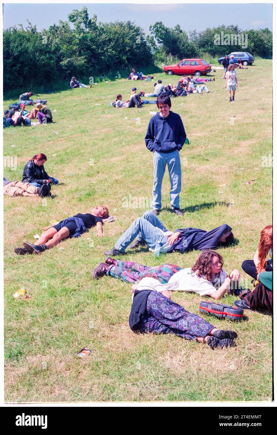 GLASTONBURY FESTIVAL, 1995: People hang out waiting for their ride in the 'bus station' area in the car park on the Monday after Glastonbury Festival finishes, Pilton Farm, Somerset, England, 26 June 1995. In 1995 the festival celebrated its 25th anniversary. There was no pyramid stage that year as it had burned down. Photo: ROB WATKINS Stock Photo