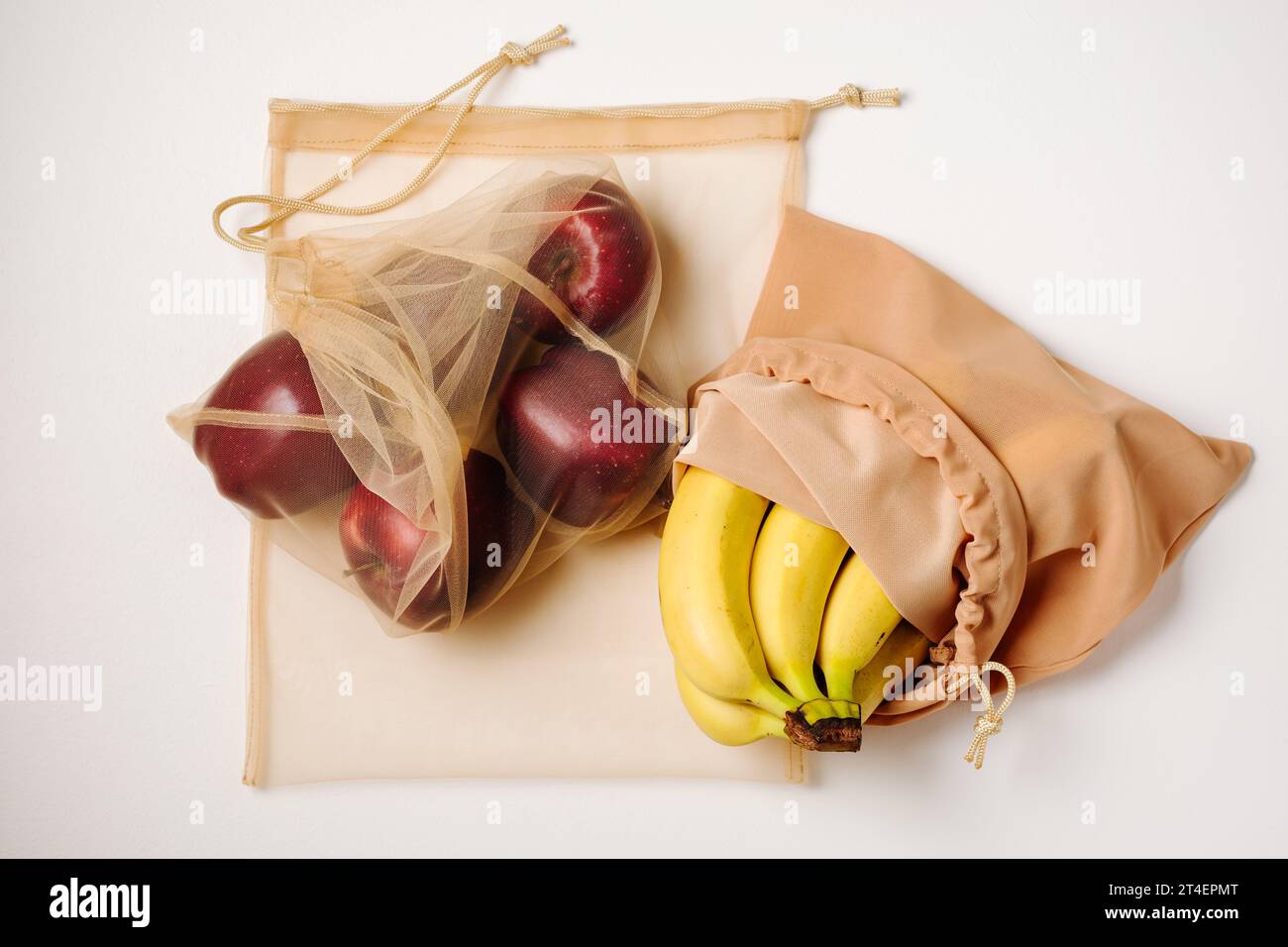 Red apples and bananas in reusable bags. Stock Photo