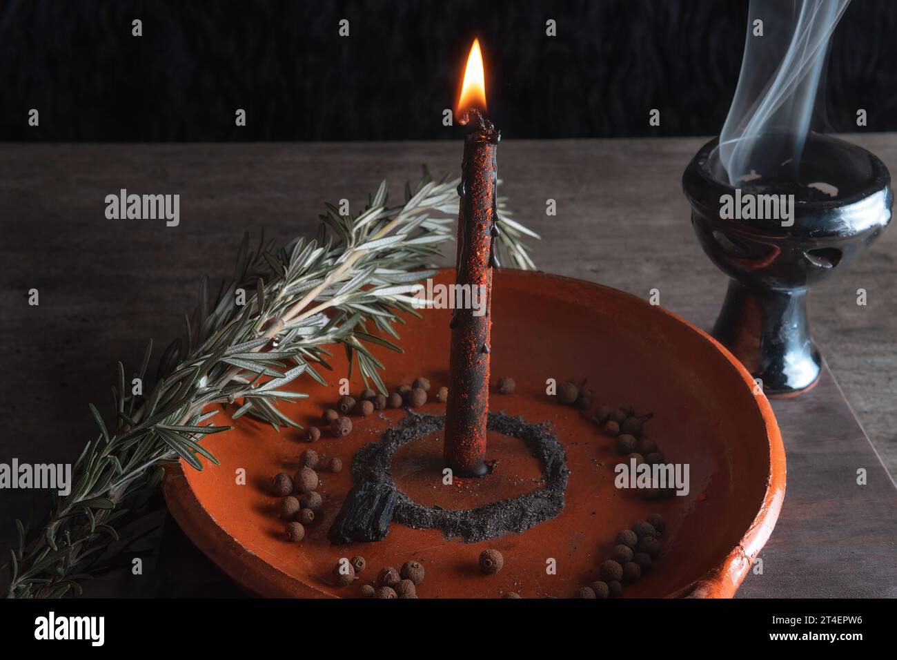 traditional ritual with fire and black candle in clay plate accompanied by pepper, sea salt, herbs and incense Stock Photo