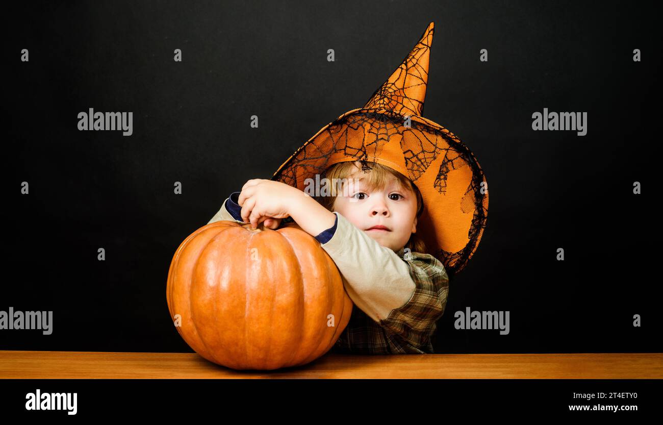 Thanksgiving day cooking. Child boy with pumpkin. Halloween kid with jack-o-lantern. Surprised kid in witch hat with Halloween pumpkin. Preparation Stock Photo