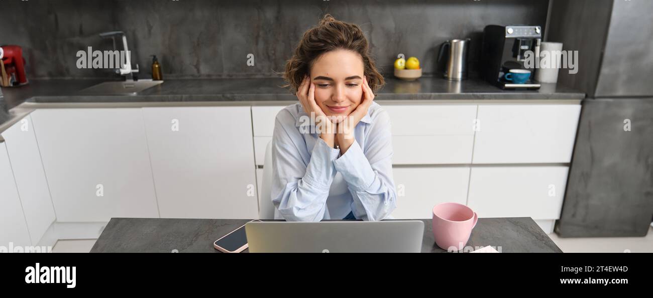 Portrait of young woman watching video on laptop, looking at computer ...