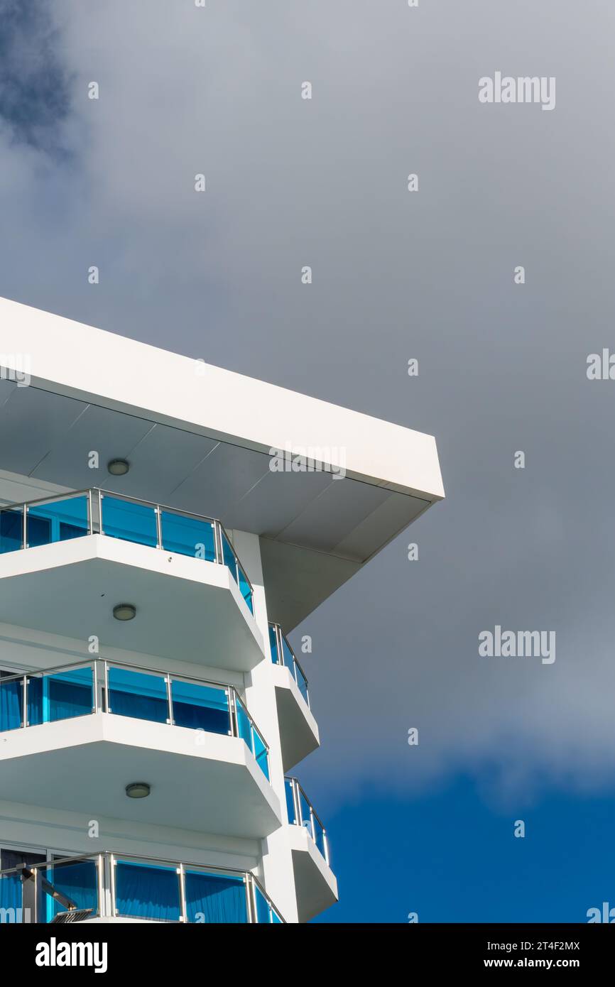 An apartment building, hotel shot from below against a blue but cloudy sky, whits with blue windows Stock Photo