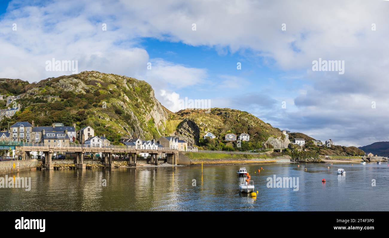 A multi image panorama of Barmouth Harbour featuring small boats in the foreground and rocky peaks in the background. Stock Photo