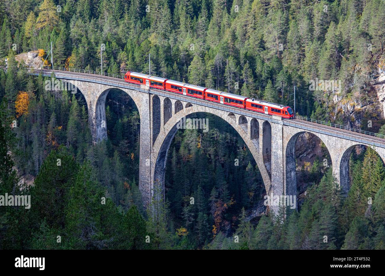 Davos Wiesen - October 2023: A red passenger train is crossing the famous Wiesener viaduct on the train line Davos - Filisur, the highest viaduct in s Stock Photo
