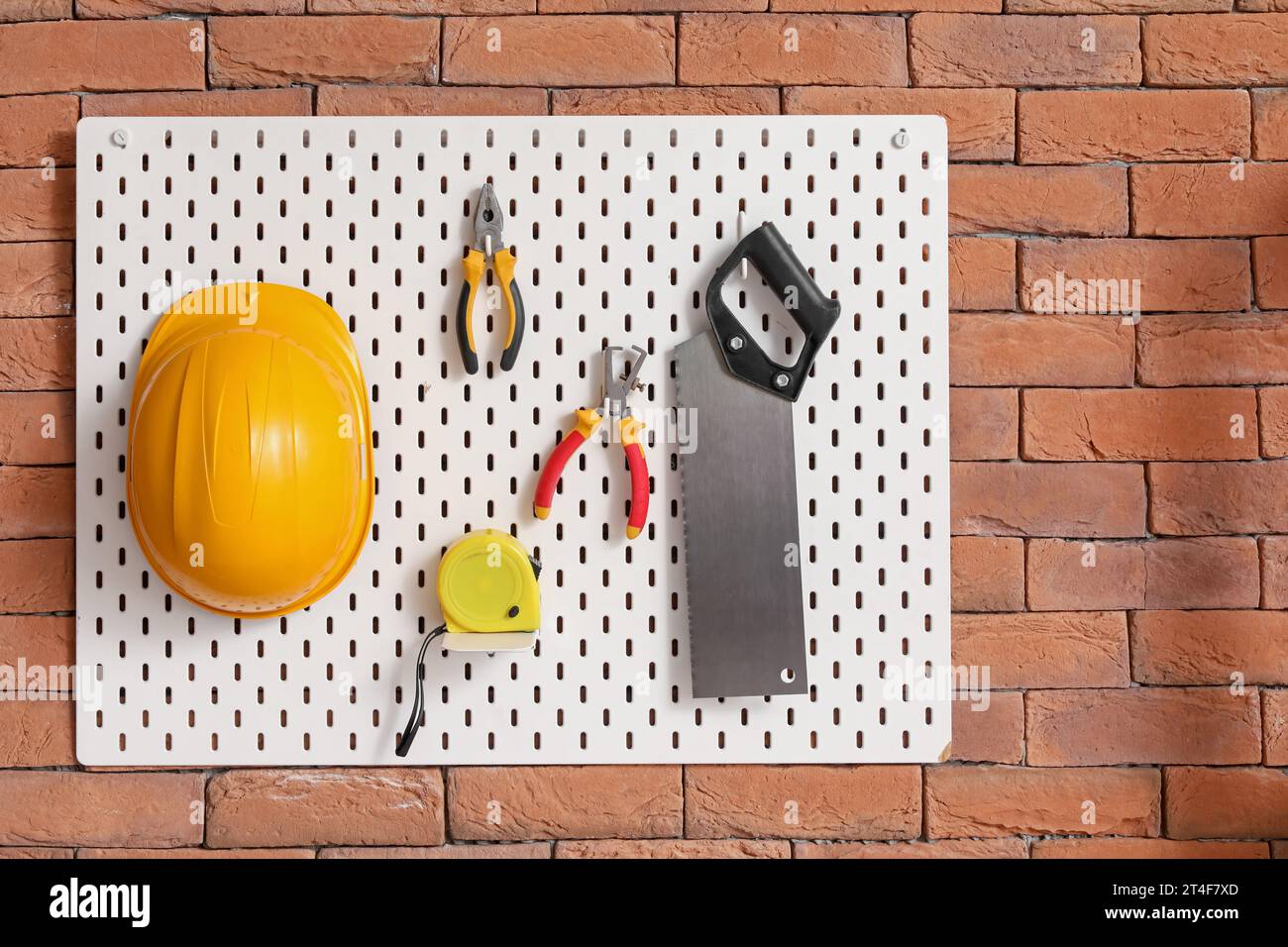 Pegboard with builder's tools on brick wall in workshop Stock Photo