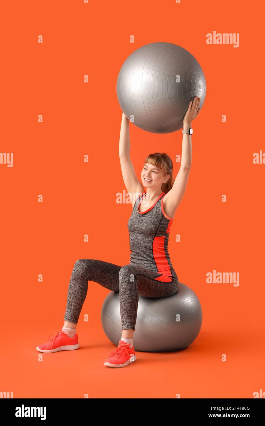 Young sporty woman with fitness balls on red background Stock Photo