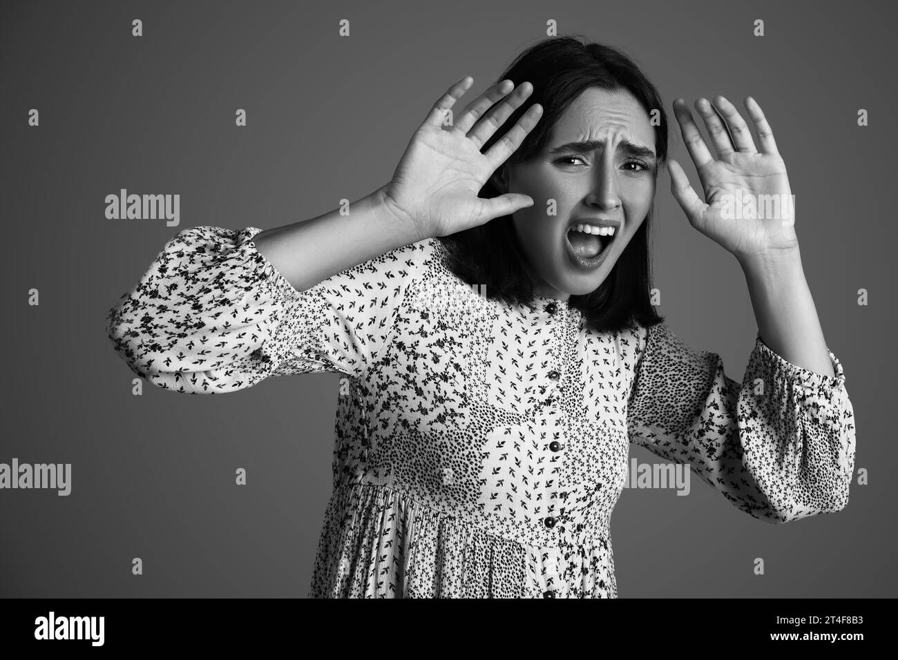 Beautiful young afraid woman screaming on grey background Stock Photo