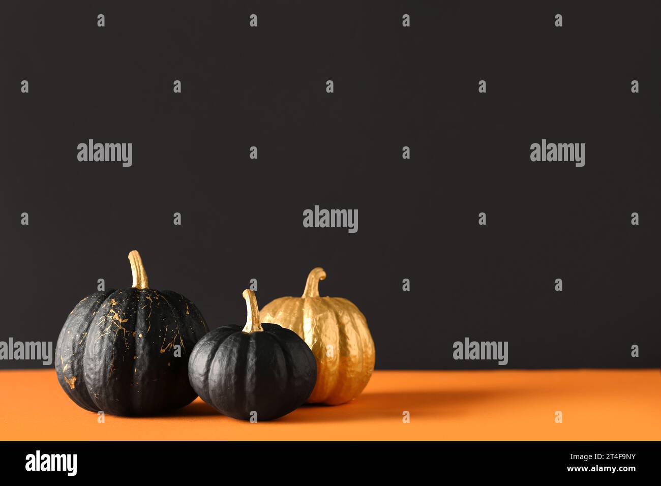 Painted pumpkins on orange table near black wall Stock Photo - Alamy