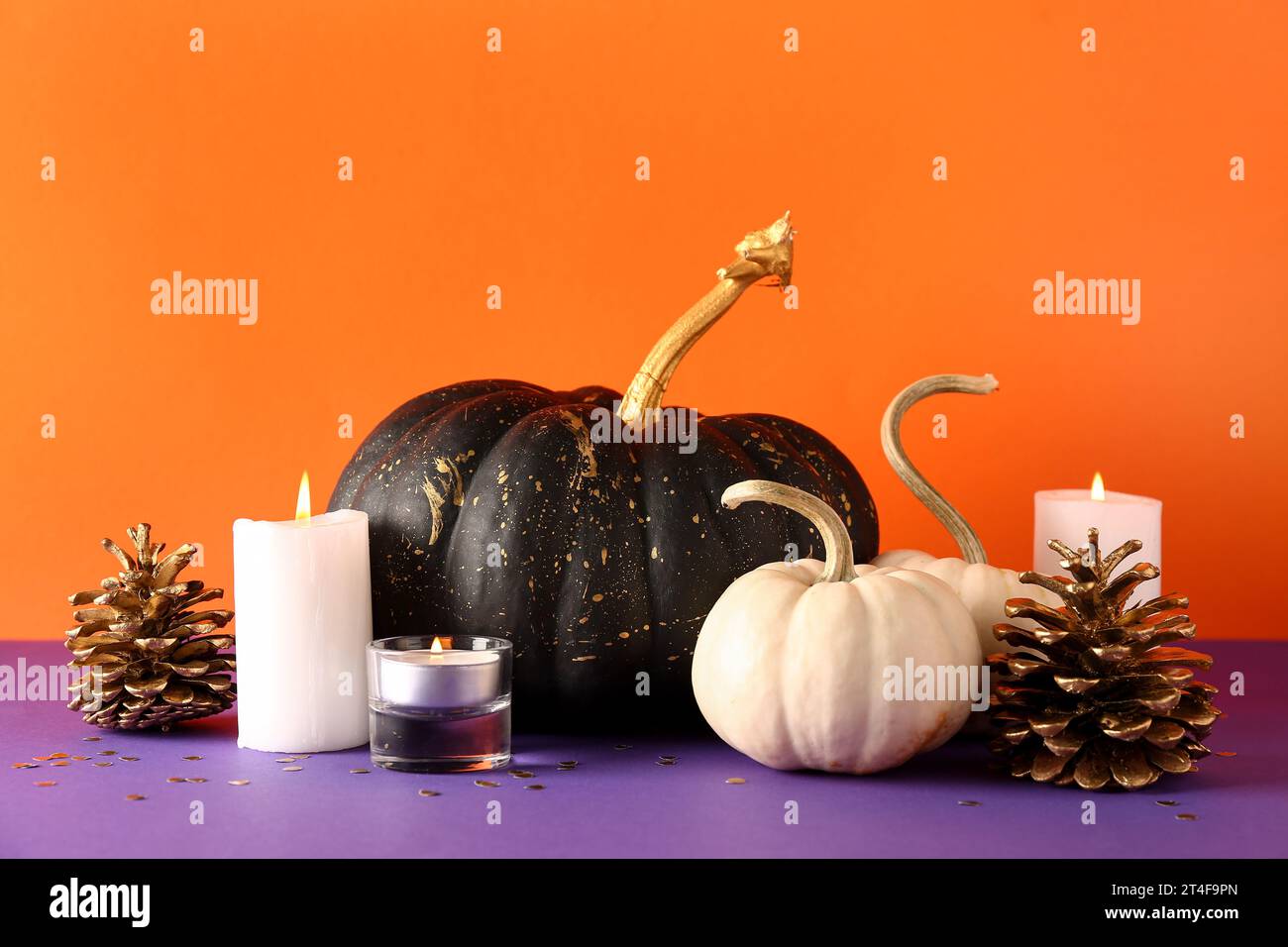 Painted pumpkins with golden cones and candles on purple table near ...