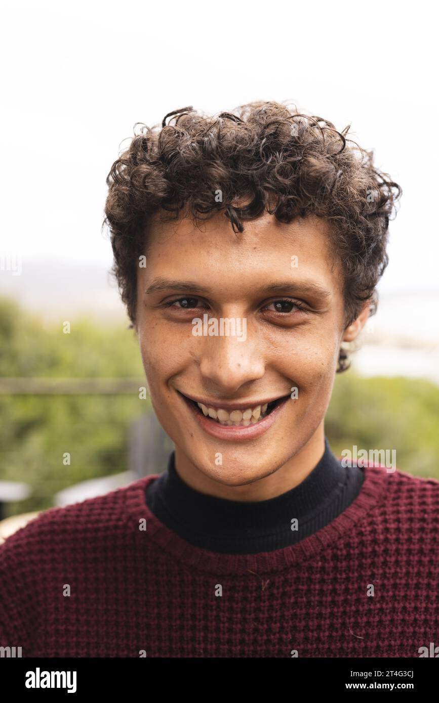 Portrait of happy biracial man with curly hair at balcony over forest view Stock Photo