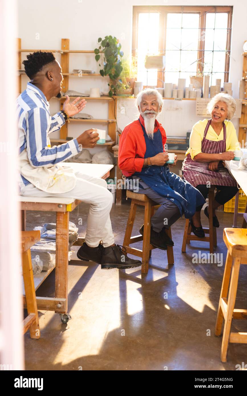 Happy diverse group of potters discussing and smiling in pottery studio ...