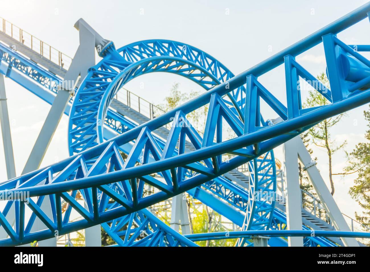 Roller coaster blue up down turn and passing loop feint, spiral train of trolleys tends to go down Stock Photo